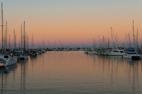 Colourful sunset reflections in a marina with yachts and boats.