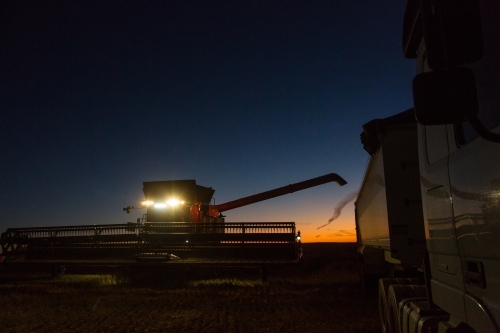 Combine harvester about to unload grain into a semi trailer truck at night