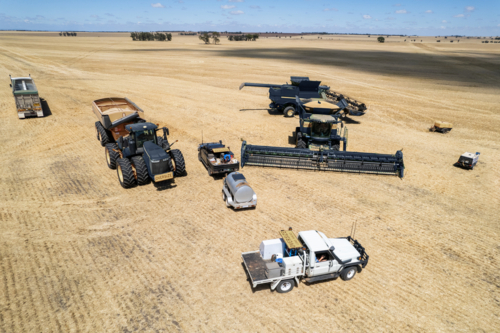 Combine harvester and tractor parked on the crop field - Australian Stock Image