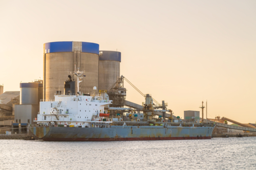 Commercial cement carrier at Port Adelaide docks viewed across the Port River at sunset - Australian Stock Image