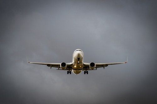 Commercial passenger jet coming in to land against a stormy sky. - Australian Stock Image