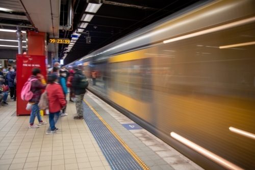 Commuters on the platform at Central Station in Sydney as a train goes past platform - Australian Stock Image