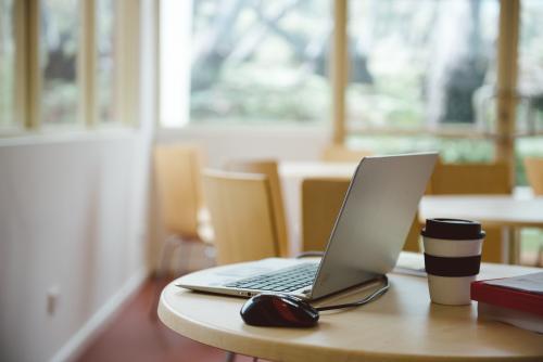 Computer on a table with take away coffee - Australian Stock Image