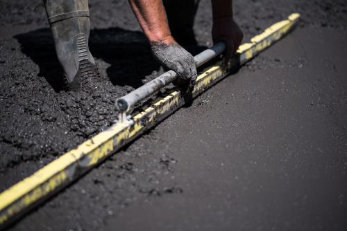 Concreter screeding black concrete - Australian Stock Image