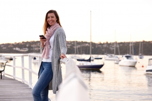 Confident woman using mobile phone on wharf - Australian Stock Image