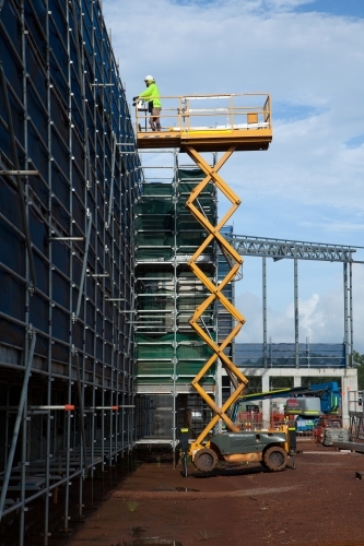 Construction worker on a scissor lift on an industrial building site - Australian Stock Image