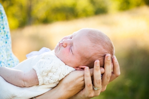 Content sleepy baby in mothers arms - Australian Stock Image