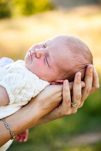 Content sleepy baby in mothers arms - Australian Stock Image