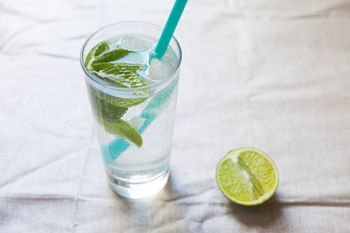 Cool glass of water with ice and mint on tabletop