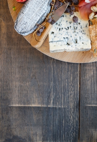 Corner of cheese platter on wooden table