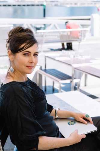 Corporate woman sitting at a Docklands cafe with her laptop - Australian Stock Image