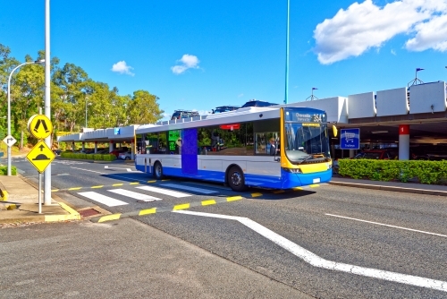 Council bus driving across pedestrian crossing on sealed roads near a shopping centre - Australian Stock Image