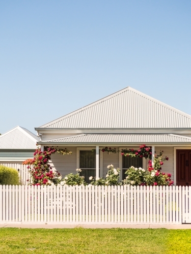 Country cottage with picket fence and red roses - Australian Stock Image