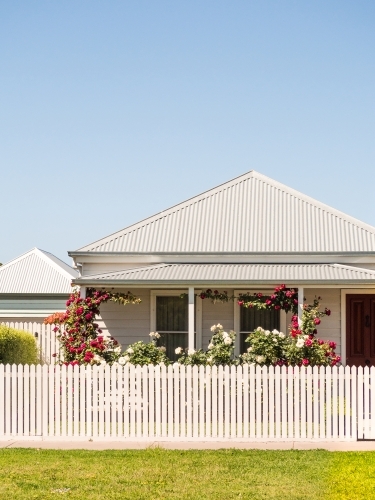 Country cottage with picket fence and red roses