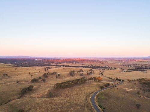 Country road winding away over hills at sunset - Australian Stock Image