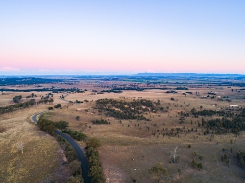 Country road winding away over hills at sunset - Australian Stock Image