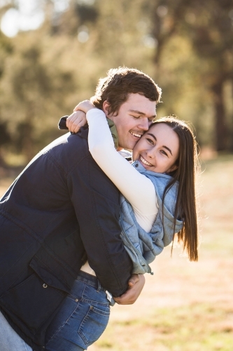Couple cuddling arms wrapped tight smiling - Australian Stock Image