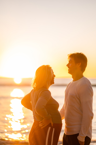 Couple enjoying maternity moments at Manly Beach during sunrise - Australian Stock Image