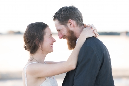 Couple on wedding day looking into each other's eyes and smiling. - Australian Stock Image