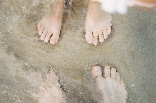 Couple's Feet in the Water on Beach