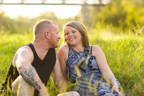Couple seated together on green grass - Australian Stock Image