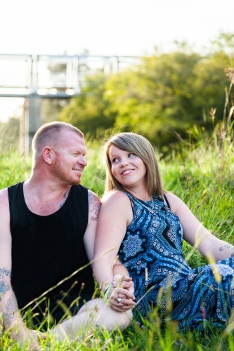 Couple seated together on green grass - Australian Stock Image