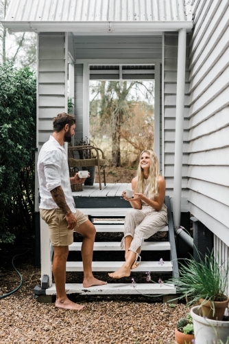 Couple talking on the steps of their front verandah - Australian Stock Image