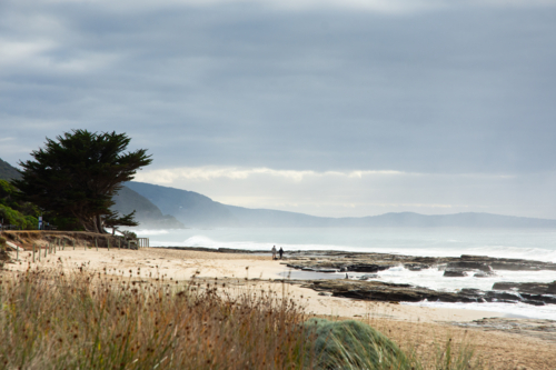 Couple walking on moody beach - Australian Stock Image