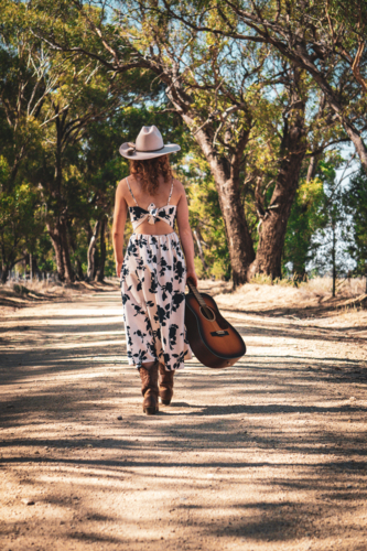 Cowgirl walking with a guitar - Australian Stock Image