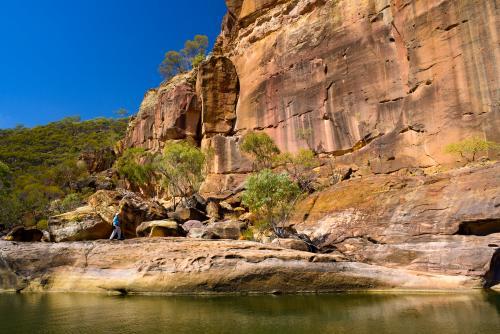 Creek in a gorge with orange sandstone rock formation and blue sky - Australian Stock Image