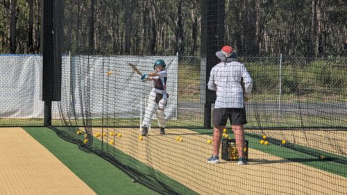 Cricket batting lesson with girl and coach during outdoor net training session - Australian Stock Image