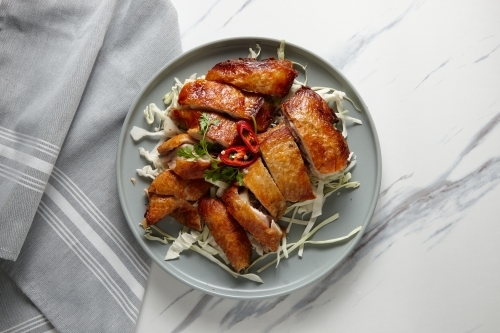 Crispy chicken served on a grey plate on top of rasp cabbage. - Australian Stock Image