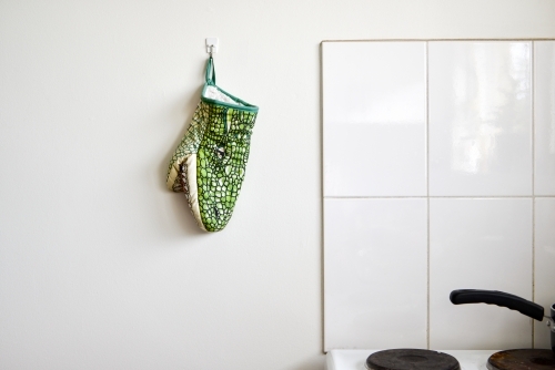 Crocodile oven glove hanging on a white kitchen wall
