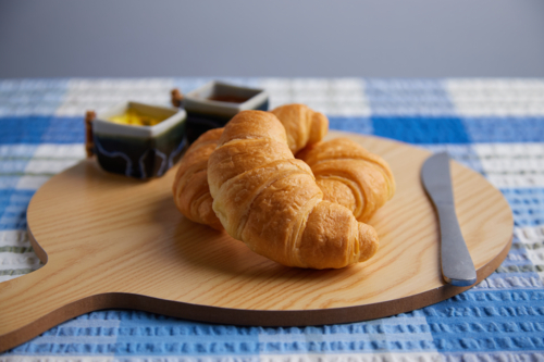 Croissants on serving board with blue tablecloth - Australian Stock Image