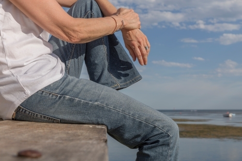 Cropped body shot of woman relaxing on timber jetty - Australian Stock Image
