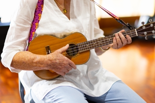 cropped view of older person playing ukulele
