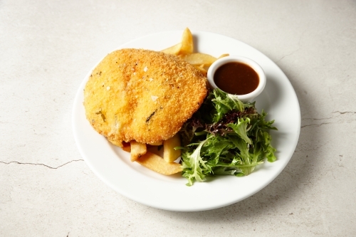 Crumbed fish with chips and salad on plate - Australian Stock Image
