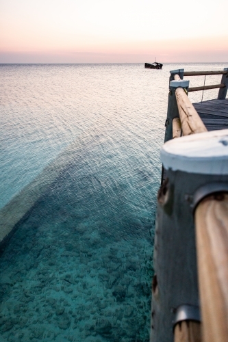 crystal clear water and jetty on heron island at sunset - Australian Stock Image