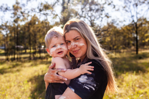 Cultural image of First nations Australian mother carrying son together on country - Australian Stock Image