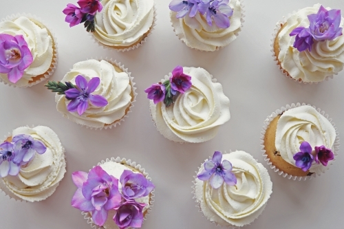 Cupcakes with purple edible flowers for tea party - Australian Stock Image
