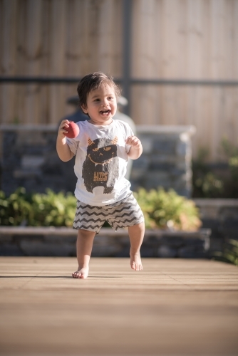 Cute 1 year old boy takes his first steps outside in his suburban backyard - Australian Stock Image