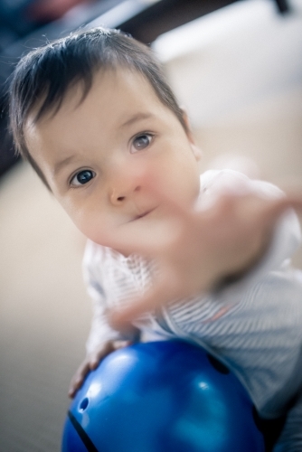 Cute 1 year old mixed race boy reaches out while playing at home - Australian Stock Image