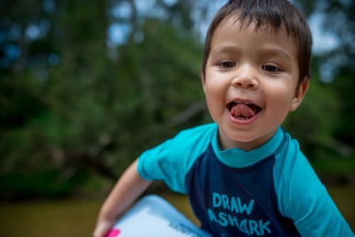 Cute 3 year old mixed race boy plays and swims in a river - Australian Stock Image