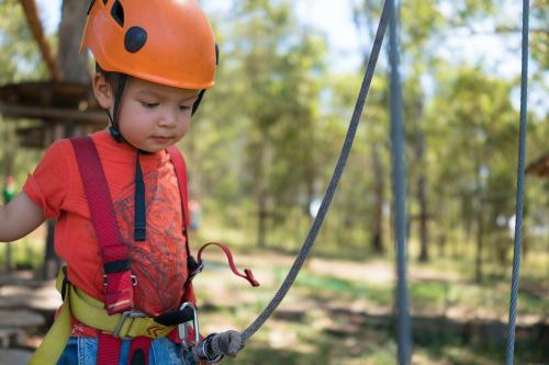 Cute 3 year old mixed race boy plays on an adventure ropes course - Australian Stock Image