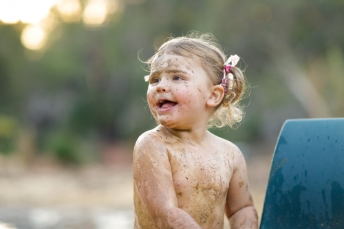 Cute little girl playing in mud - Australian Stock Image