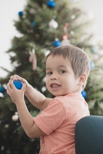 Cute mixed race boy hanging decorations on Christmas tree