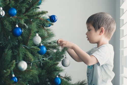 Cute mixed race boy hanging decorations on their Christmas tree