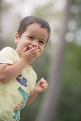 Cute mixed race boy playing in a park outside among the trees - Australian Stock Image