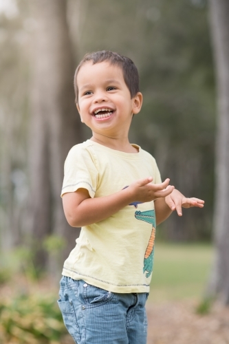 Cute mixed race boy playing in a park outside among the trees
