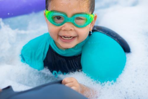 Cute mixed race boy plays in the bubbles of a backyard spa - Australian Stock Image